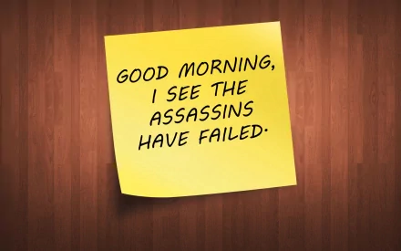 HD desktop wallpaper featuring a yellow sticky note on a wooden background with the humorous message: GOOD MORNING, I SEE THE ASSASSINS HAVE FAILED.