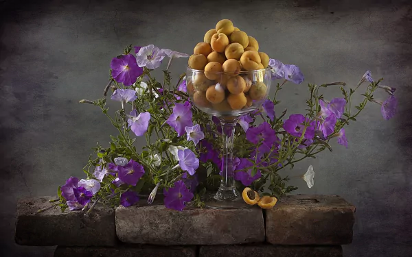 Still life HD wallpaper featuring a glass goblet filled with peaches surrounded by vibrant purple flowers against a dark, textured background.