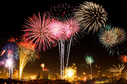 HD desktop wallpaper featuring vibrant fireworks over Leipzig, Germany. The night sky bursts into a colorful display, illuminating the city's silhouette below. A stunning piece of photography capturing festive fireworks.