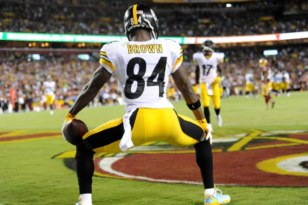 HD wallpaper of a player in a black and yellow uniform, jersey number 84, on a football field, posing confidently.