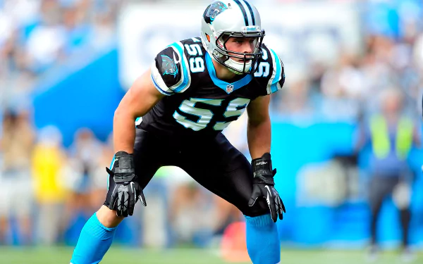 HD desktop wallpaper of a football player in a black and blue uniform, poised for action on the field.