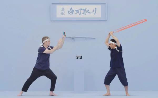 HD desktop wallpaper for 1-2-Switch featuring two people in a mock sword fight stance against a blue backdrop with Japanese text overhead.