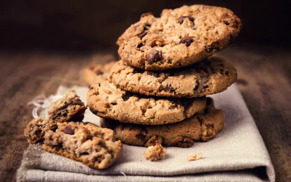 Close-up of a stack of chocolate chip cookies on a cloth, captured in 4K Ultra HD, creating a rich and inviting PC desktop wallpaper background.