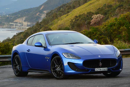 Blue Maserati GranTurismo supercar parked on a coastal road, high-detail car and vehicle image for 4K Ultra HD PC desktop wallpaper and background.