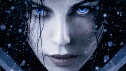 Close-up of a character with piercing blue eyes in a snowy scene from the Underworld: Awakening and Underworld: Evolution movies, featured as an HD PC desktop wallpaper.