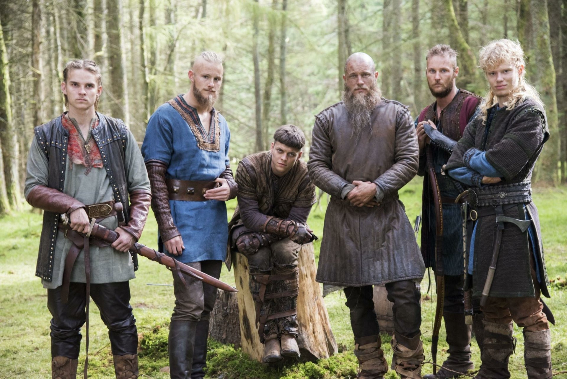 HD desktop wallpaper featuring the main cast of the TV show Vikings (2013) standing in a forest, dressed in period-appropriate Viking attire.