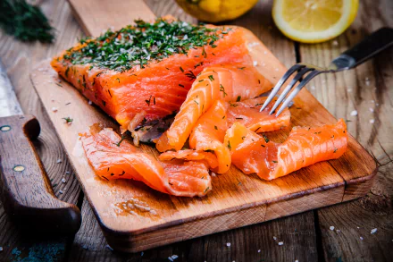 Close-up of seasoned salmon fillet on a wooden cutting board with a fork, lemon slices, and herbs, displayed as a 4K Ultra HD still life seafood wallpaper.