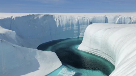 HD desktop wallpaper from the movie Chasing Ice: sweeping arctic scene of towering ice cliffs framing a winding turquoise meltwater channel under a clear blue sky.