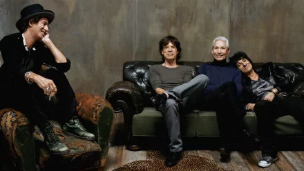 The Rolling Stones band members relaxed on vintage leather sofas, captured in an HD music-themed PC desktop wallpaper and background.