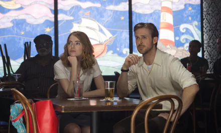 HD desktop wallpaper of Emma Stone and Ryan Gosling from the movie La La Land, sitting at a table with colorful, nautical-themed artwork in the background.
