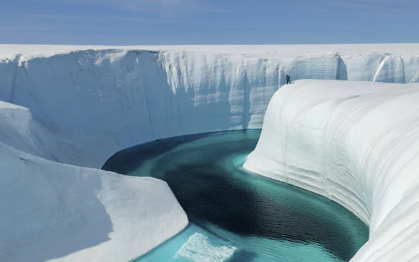 HD desktop wallpaper from the movie Chasing Ice: sweeping arctic scene of towering ice cliffs framing a winding turquoise meltwater channel under a clear blue sky.