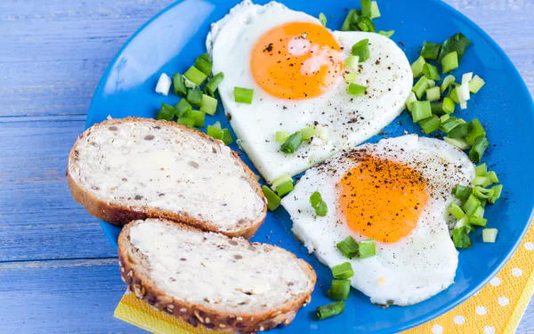 5K Ultra HD PC desktop wallpaper: heart-shaped fried eggs with bright yolks on a blue plate, chopped green onions and sliced buttered multigrain bread.
