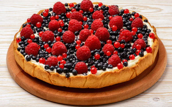 A vibrant tart topped with raspberries, blueberries, currants, and cream on a wooden board, captured in 4K Ultra HD for a PC desktop wallpaper.