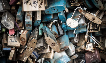Close-up of numerous man-made locks clustered together, featuring a romantic heart-shaped lock, captured in HD for a striking desktop wallpaper background.