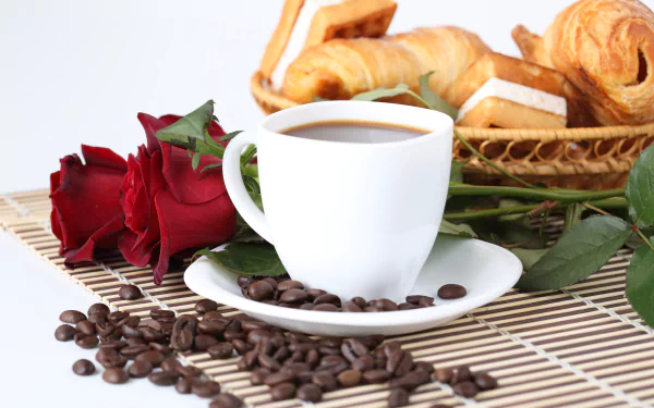 8K Ultra HD PC desktop wallpaper: still life of a white coffee cup on a saucer with scattered coffee beans, red roses and a basket of croissants.