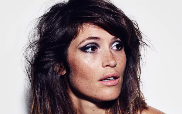 Close-up 4K Ultra HD image of English actress Gemma Arterton with brunette hair, brown eyes, and freckles, captured against a plain background.