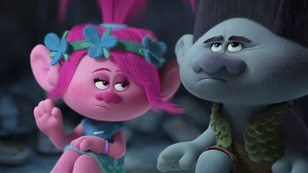 HD desktop wallpaper featuring characters from the movie Trolls. A pink-haired troll with flowers and a gray troll share an expressive moment in a whimsical setting.