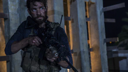 HD PC desktop wallpaper: bearded soldier in tactical gear aims a rifle inside a dim concrete structure — scene from the movie 13 Hours: The Secret Soldiers of Benghazi.