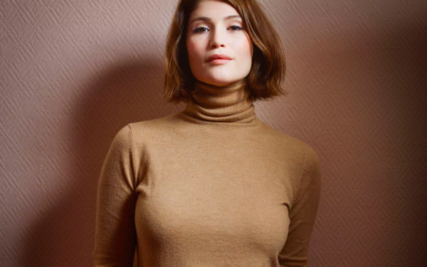 HD desktop wallpaper featuring English actress Gemma Arterton with short brunette hair and brown eyes, wearing a tan turtleneck against a textured brown background.
