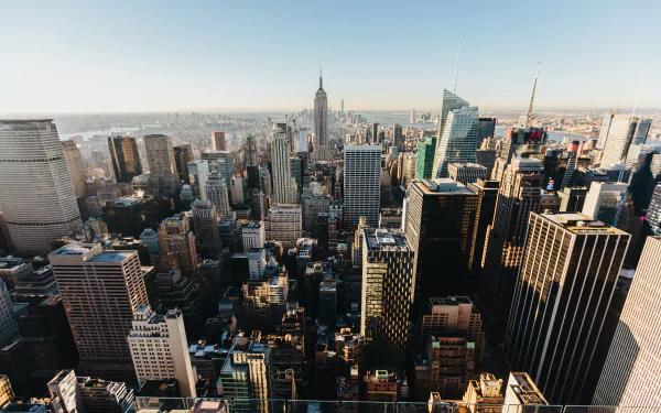 A 4K Ultra HD cityscape of New York featuring the Empire State Building and numerous skyscrapers stretching across the horizon under a clear sky.