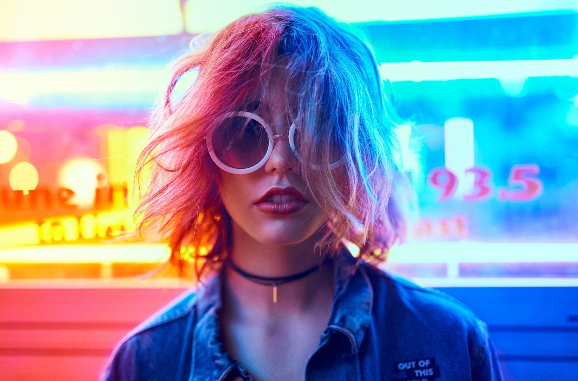 HD desktop wallpaper featuring a blonde woman with short hair, wearing sunglasses and lipstick, illuminated by vibrant neon lights.