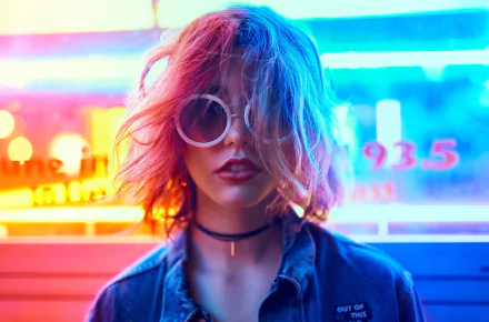 HD desktop wallpaper featuring a blonde woman with short hair, wearing sunglasses and lipstick, illuminated by vibrant neon lights.