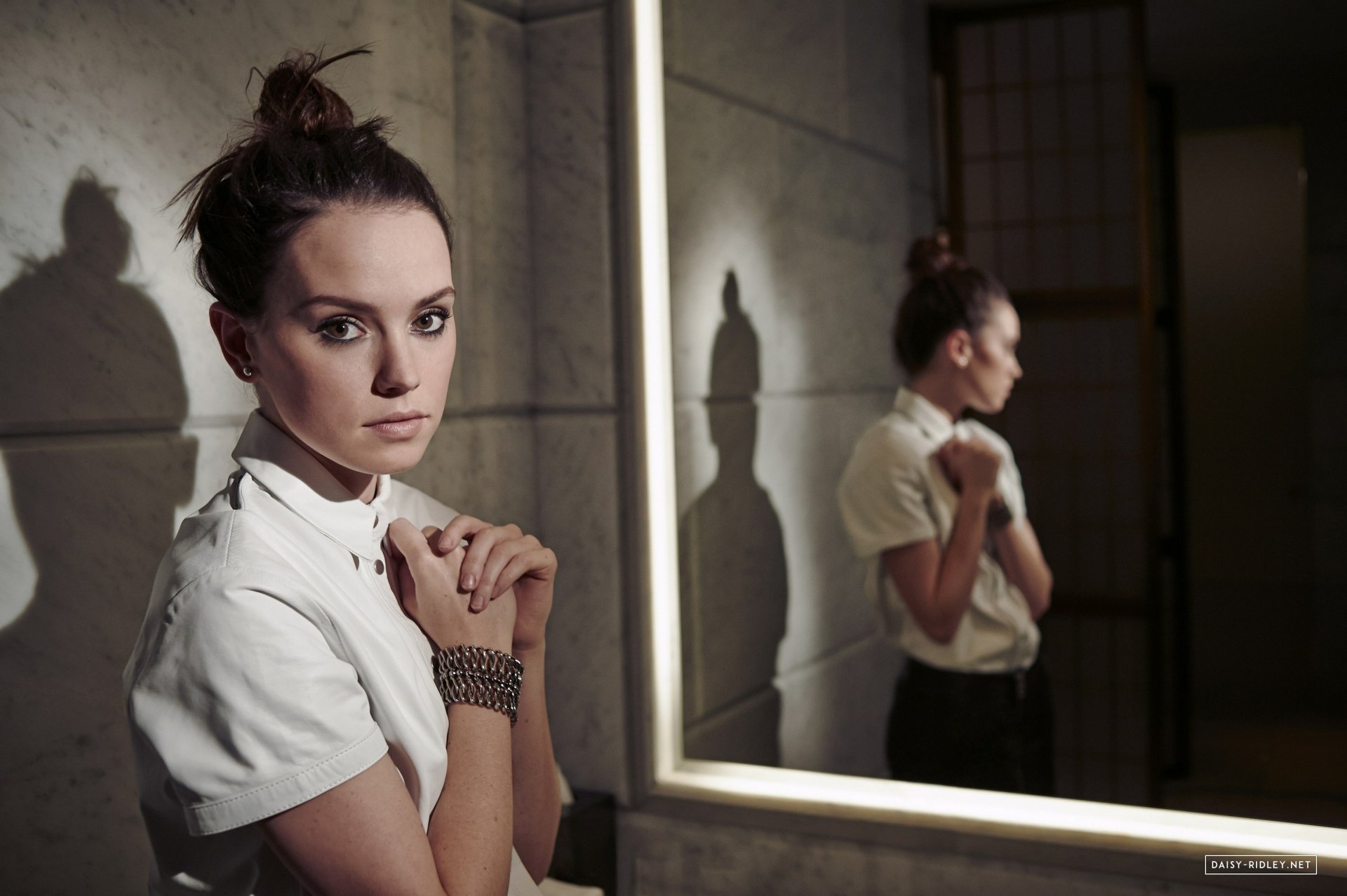 Brunette actress Daisy Ridley poses thoughtfully by a mirror, captured in this HD PC desktop wallpaper and background.