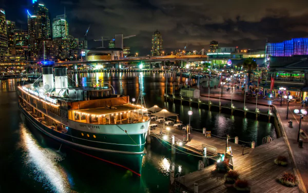 Night view of Sydney's Darling Harbour marina featuring the illuminated South Steyne Floating Restaurant boat and city lights, captured in HD for a desktop wallpaper.