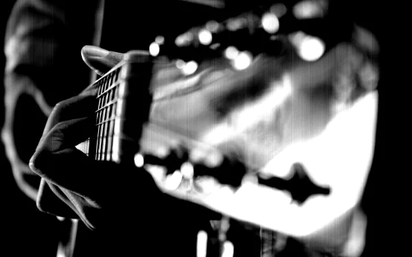 A close-up of a musician's hand skillfully playing a guitar, captured in striking black and white. This HD image encapsulates the essence of jazz music.