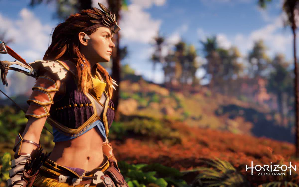 HD desktop wallpaper featuring Aloy from the video game Horizon Zero Dawn, standing in a vibrant, natural landscape with lush greenery and a clear blue sky.