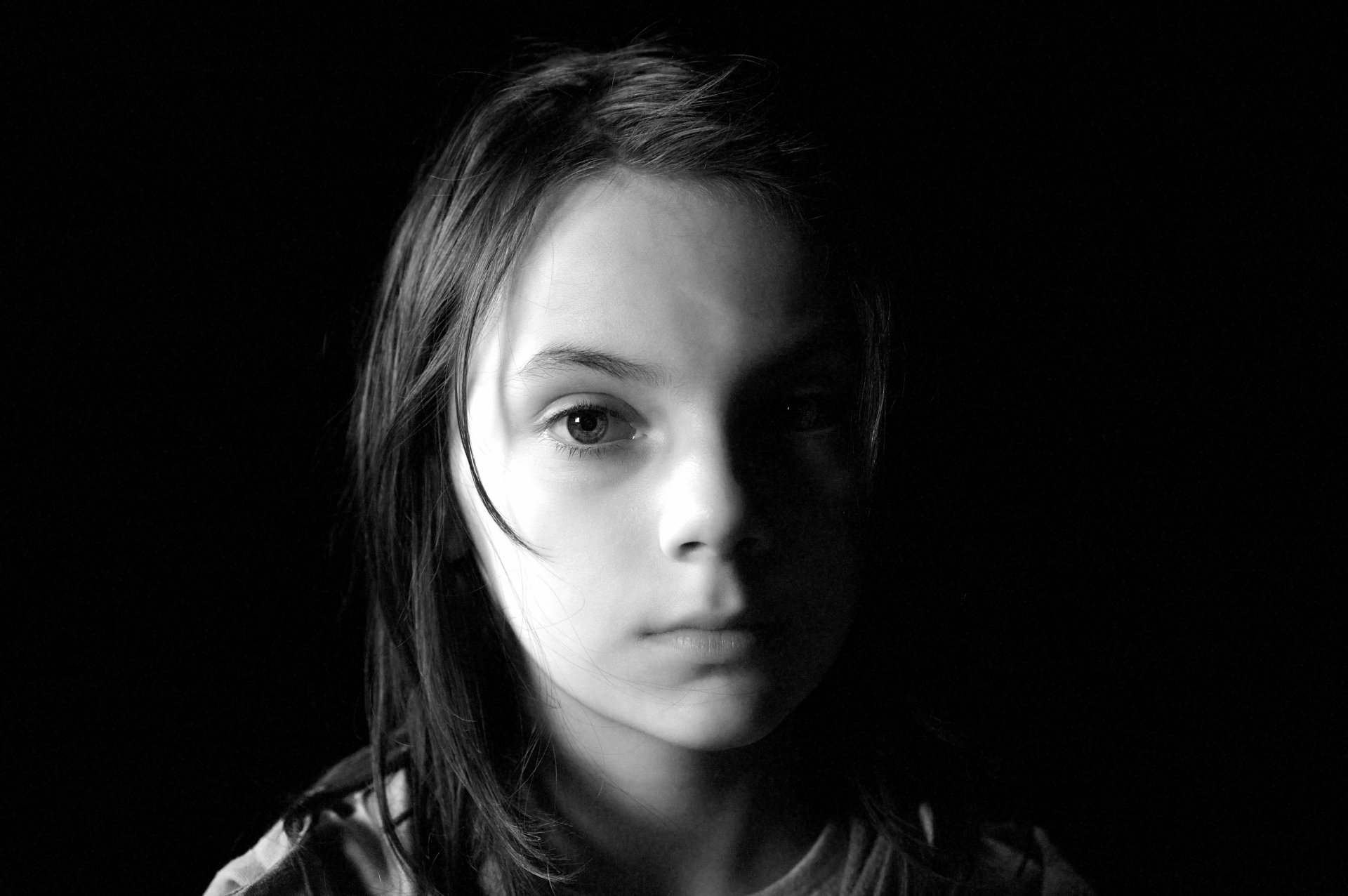 Black and white HD wallpaper featuring Dafne Keen as Laura Kinney (X-23) from the movie Logan. The image portrays a close-up shot with a dark background.