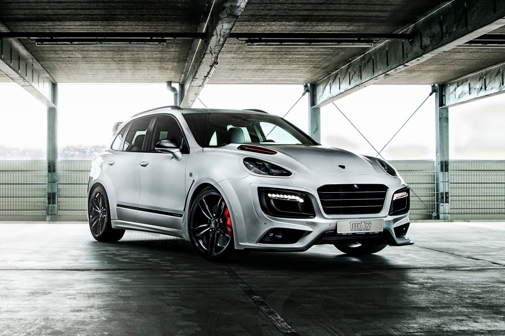 White Porsche Cayenne SUV in a concrete parking garage with dramatic lighting — sleek white car rendered as a 2K Quad HD PC desktop wallpaper.