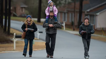 HD PC desktop wallpaper showing a bearded man carrying a young girl on his shoulders, walking with two adults down a quiet suburban street — cinematic movie still.