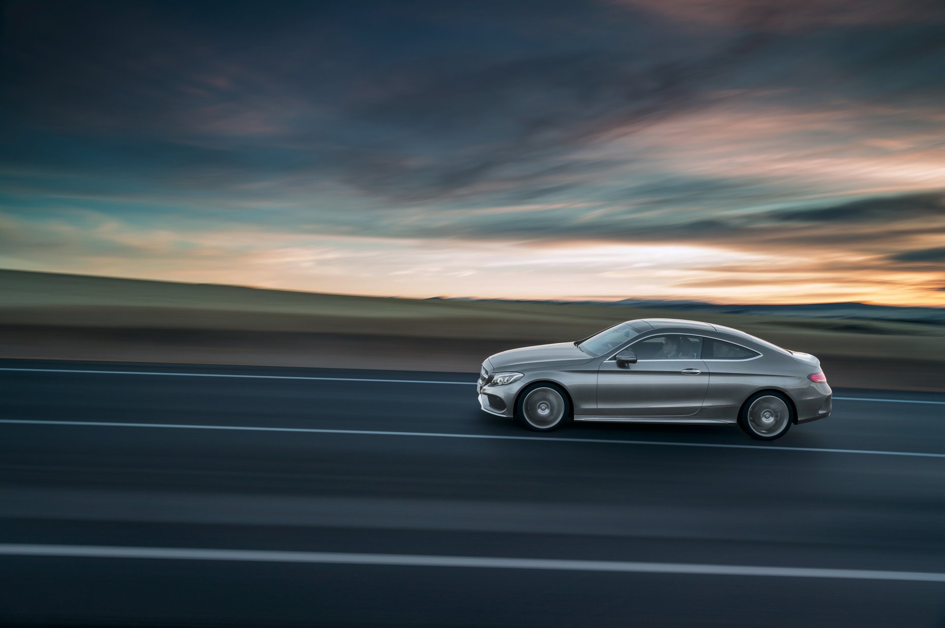 Silver Mercedes-Benz C-Class coupe gliding along a highway at sunset with motion blur — 4K Ultra HD PC desktop wallpaper and background of a sleek car/vehicle.
