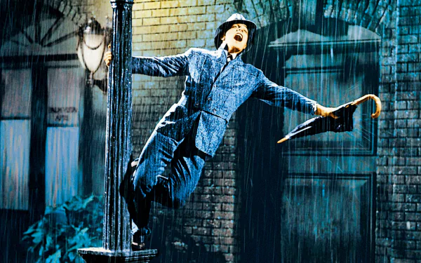 HD desktop wallpaper featuring Gene Kelly joyfully dancing with an umbrella in the rain, a classic scene from the movie Singin' In The Rain.