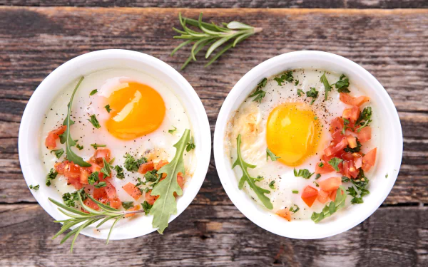 HD desktop wallpaper featuring two bowls of cooked eggs garnished with herbs and diced tomatoes on a rustic wooden surface, showcasing fresh food and egg themes.