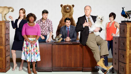 HD wallpaper featuring the cast of the TV show Trial & Error. The cast is posing around a desk with eclectic props, including a bear and a man in roller skates holding a dog.