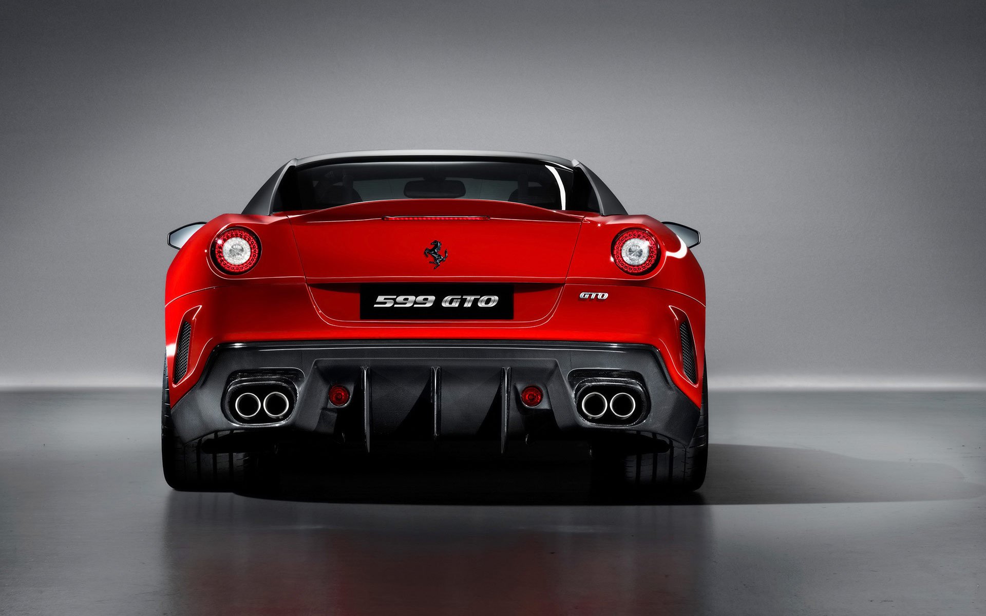 Rear view of a red Ferrari 599 GTO grand tourer vehicle with quad exhausts and aggressive diffuser, presented as an HD PC desktop wallpaper background.