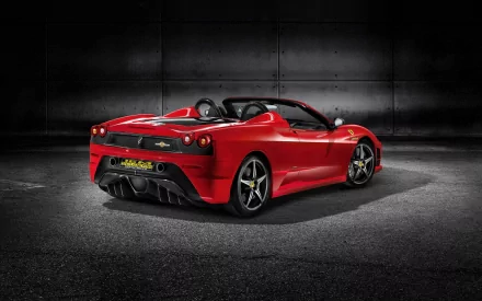 Red Ferrari Scuderia Spider 16M convertible, rear three-quarter view in a dark industrial setting — HD PC desktop wallpaper of a Ferrari sports car.