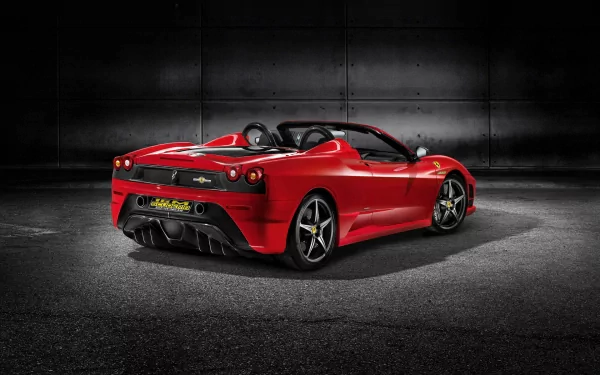 Red Ferrari Scuderia Spider 16M convertible, rear three-quarter view in a dark industrial setting — HD PC desktop wallpaper of a Ferrari sports car.
