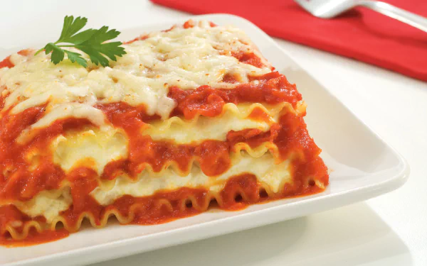 Close-up of a cheesy lasagna slice on a white plate, captured in HD for a vibrant PC desktop wallpaper featuring a delicious meal.