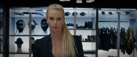 HD desktop wallpaper featuring Charlize Theron as Cipher in the movie The Fate of The Furious with a backdrop of tactical gear and equipment showcased in the background.