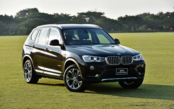 Black BMW X3 SUV on a grassy field at sunset — 4K Ultra HD PC desktop wallpaper/background.