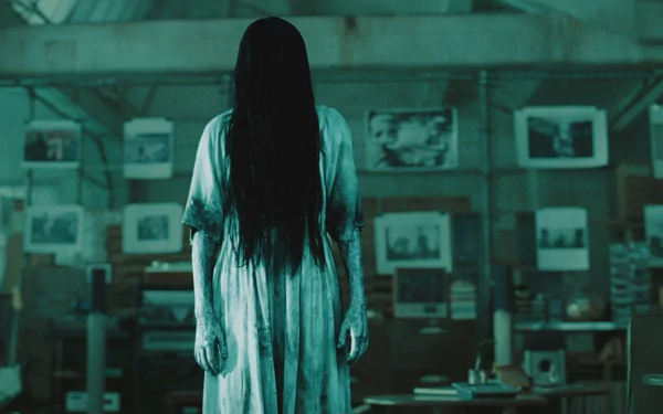 HD PC desktop wallpaper from the movie The Ring (2002) featuring a ghostly figure with long black hair standing in a dimly lit room filled with photos.