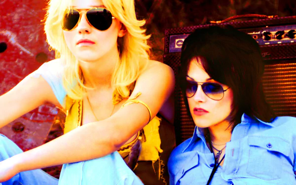 HD desktop wallpaper featuring Kristen Stewart and Dakota Fanning in character from the movie The Runaways, both wearing sunglasses against a vibrant backdrop.