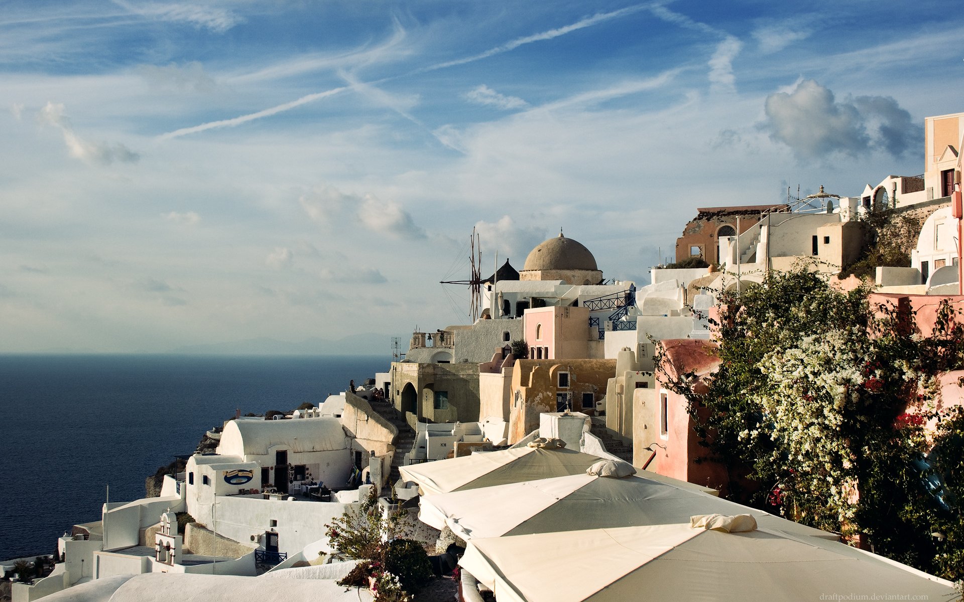 HD desktop wallpaper of a scenic coastal city with white and pastel buildings sprawled on a hillside, against a backdrop of the sea and a partly cloudy sky.