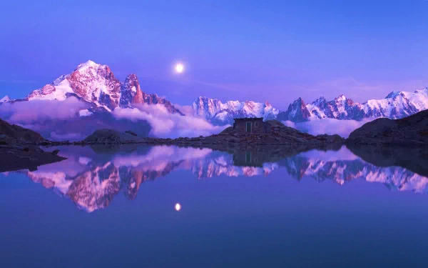 HD desktop wallpaper featuring a serene winter scene with snow-covered mountains reflected in a calm lake under a full moon, showcasing the stunning beauty of nature.