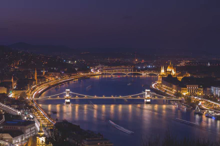 Nighttime 4K cityscape of Budapest featuring the illuminated Chain Bridge and Margaret Bridge over the river, with historic buildings glowing along the waterfront.