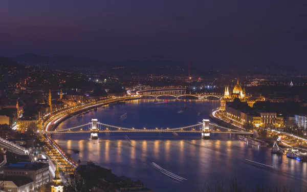Nighttime 4K cityscape of Budapest featuring the illuminated Chain Bridge and Margaret Bridge over the river, with historic buildings glowing along the waterfront.