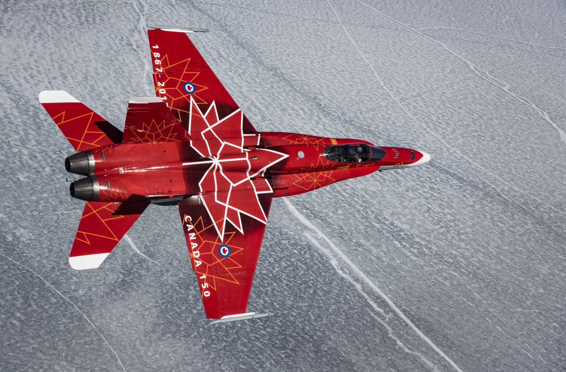 A red McDonnell Douglas CF-18 Hornet jet fighter with white maple leaf design flies over a patterned icy surface, captured in 4K Ultra HD detail.